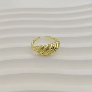 Gedetailleerd macro-overzicht van een vergulde open croissantring met elegante gedraaide textuur