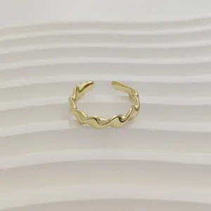 Gedetailleerde macro-opname van een minimalistische gouden golfring op witte ondergrond