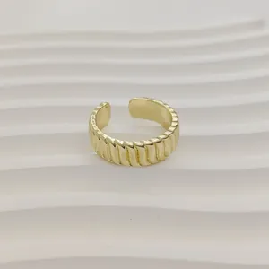 Detailopname van een minimalistische goudkleurige open ring met verticale ribbels