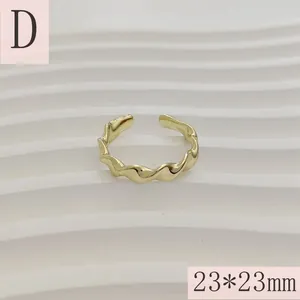 Gedetailleerd macro-overzicht van een vergulde golvende geometrische open ring op wit