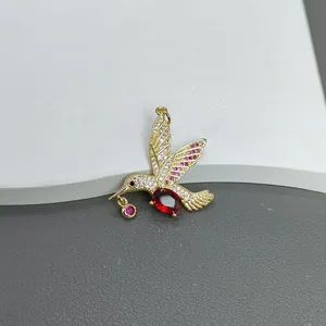 Detailansicht eines exquisiten goldenen Kolibri-Anhängers mit Zirkonia und roten Edelsteinen