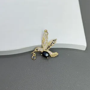 Nahaufnahme eines vergoldeten Kolibri-Anhängers mit funkelnden weißen Zirkonia-Steinen.