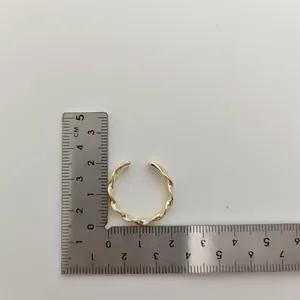 Minimalistische gouden open draairing gemeten op een metalen centimeterliniaal.