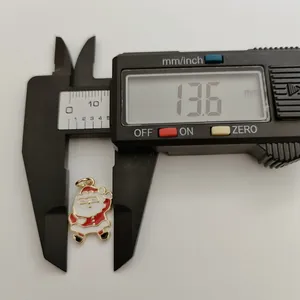 Nahaufnahme eines Santa Claus Emaille-Anhängers mit digitalem Messschieber gemessen, 13,6 mm