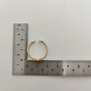 Goudkleurige open ring in de vorm van een kroon gemeten met een metalen liniaal op wit