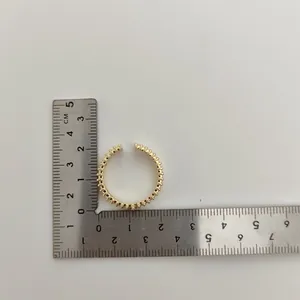 Meting van de diameter van een gouden kroonring met een metalen liniaal op wit vlak.