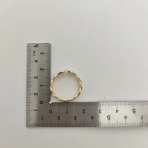 Detailopname van een goudkleurige gevlochten ring gemeten met een metalen liniaal