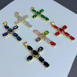 Vista detallada de varios colgantes de cruz de circonita colorida con baño de oro para joyería.