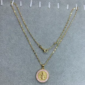Vista detallada de un collar con medalla de San Benito y borde de concha rosa.