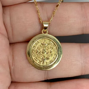 Primer plano del colgante medalla de San Benito dorado con detalles en relieve religioso