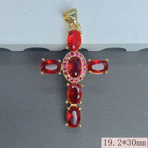 Primer plano detallado de un colgante de cruz chapado en oro con circonitas rojas y rosas