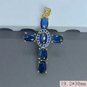 Vista detallada de un colgante de cruz religiosa chapado en oro con circones azules
