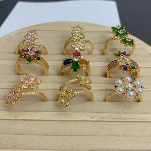 Vista detallada de varios anillos de flores dorados con circonitas de colores y perlas