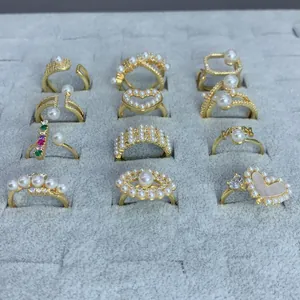 Detalle de una colección de anillos dorados con perlas y corazones en bandeja gris