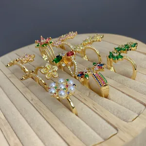 Vista detallada de varios anillos dorados con perlas, circonitas de colores y flores.