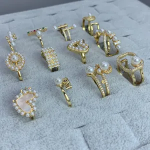 Colección de elegantes anillos dorados con perlas y circonitas en bandeja terciopelo