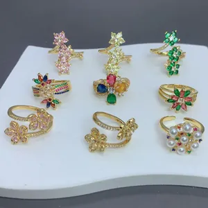 Vista detallada de anillos florales bañados en oro con circonitas de colores y perlas.