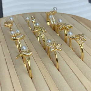 Detailansicht goldener verstellbarer Ringe mit Perlen und funkelnden Zirkonia-Akzenten.