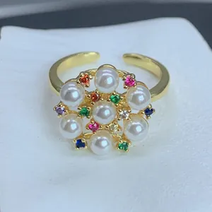 Primer plano de un anillo de flor dorado con perlas blancas y circonitas multicolores
