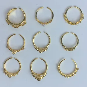 Dettaglio ravvicinato di nove anelli a corona d'oro regolabili con zirconi e perle lucide.
