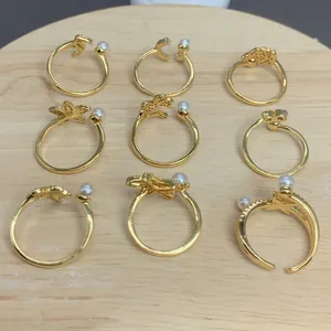 Detailansicht von neun vergoldeten verstellbaren Ringen mit Perlen und Anhängern