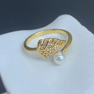 Nahaufnahme eines verstellbaren Goldrings mit mikrovergoldetem Zirkonia-Blatt und Perlendetail