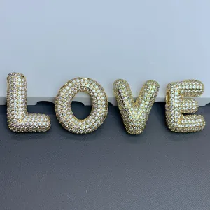 Gros plan de breloques lettres LOVE dorées pavées de zircons pour bijoux à faire soi-même.