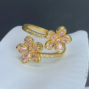 Detalle de cerca de un anillo abierto chapado en oro con dos flores de circón rosa