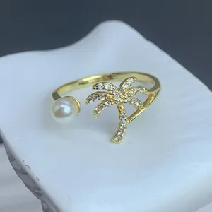 Nahaufnahme eines verstellbaren Goldrings mit kristallbesetzter Palme und Perle