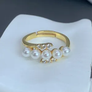 Primer plano de un elegante anillo dorado con con cinco perlas y detalles de circón