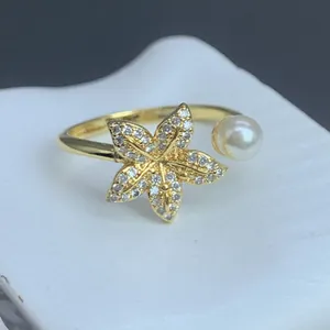 Detailaufnahme eines eleganten goldenen Blumenrings mit funkelnden Zirkonia und Perle.