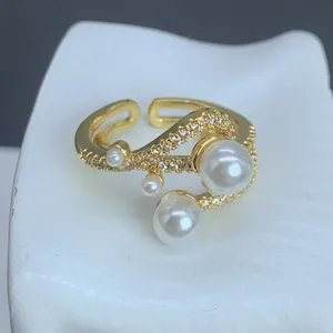 Vista detallada de un anillo ajustable dorado con perlas elegantes y circonitas brillantes