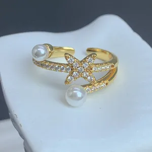 Detailansicht eines vergoldeten verstellbaren Rings mit Zirkonstern und Perlen