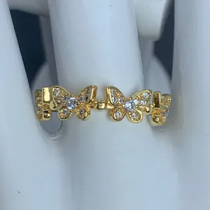 Dettaglio ravvicinato di un anello dorato con motivi a farfalla e intarsi di zirconi.