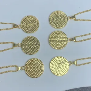 Detalle de seis colgantes medalla de San Benito en oro con intrincados patrones de textura.