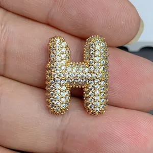 Vue détaillée d'un pendentif lettre H doré entièrement serti de cristaux brillants.
