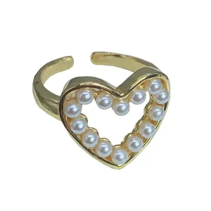 Elegante anillo ajustable de oro con una pieza central de corazón con perlas brillantes