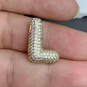 Vue rapprochée d'un pendentif en forme de lettre L doré serti de zircons cubiques.