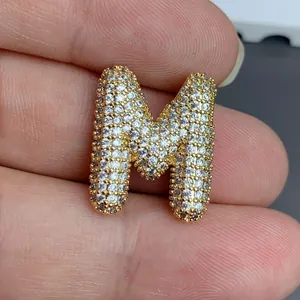 Gros plan d'un pendentif lettre M doré étincelant pavé de pierres pour bijoux DIY