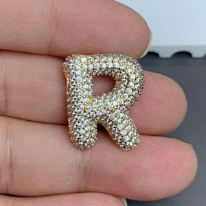 Gros plan détaillé d'un pendentif lettre R doré serti de pierres de zircone cubique claires