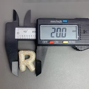 Pied à coulisse mesurant un pendentif lettre R pavé d'or, largeur 20,0 mm.