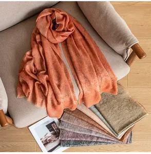 Close-up detail of luxury cashmere shawl with thistle jacquard pattern in sunset orange color