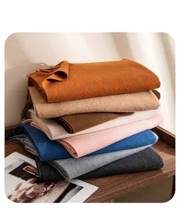 Close-up detail showing a stack of soft wool scarves with elegant fringe in diverse colors