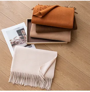 Soft wool blend scarves with tassels in autumn earth tones, folded on wooden floor
