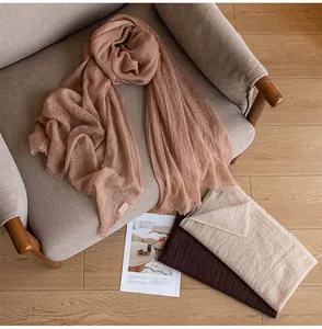 Soft dusty pink cloud yarn cashmere scarf draped over a cozy armchair detail