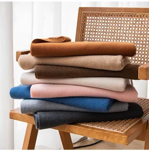 Soft wool blend solid color scarves in multiple shades displayed on a vintage rattan chair