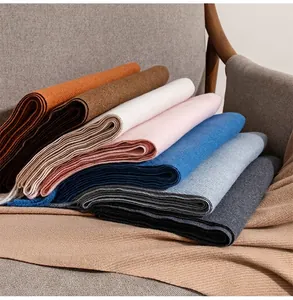 Detailed macro view of multi-colored wool blend scarves with soft fringe details on a chair.