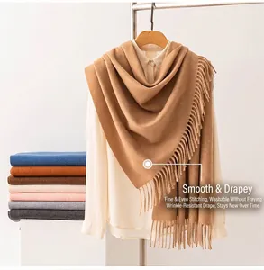 Close-up of camel wool scarf with tassel fringe on a white blouse.
