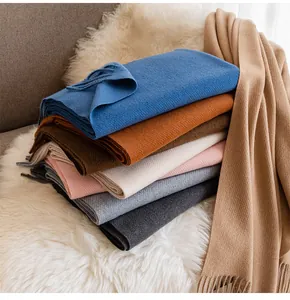 Detailed macro shot of stacked soft wool scarves with elegant fringe in various winter colors.