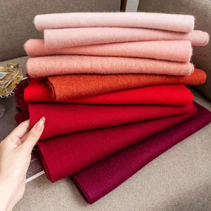Detailed texture of folded solid color wool scarves in a warm red gradient